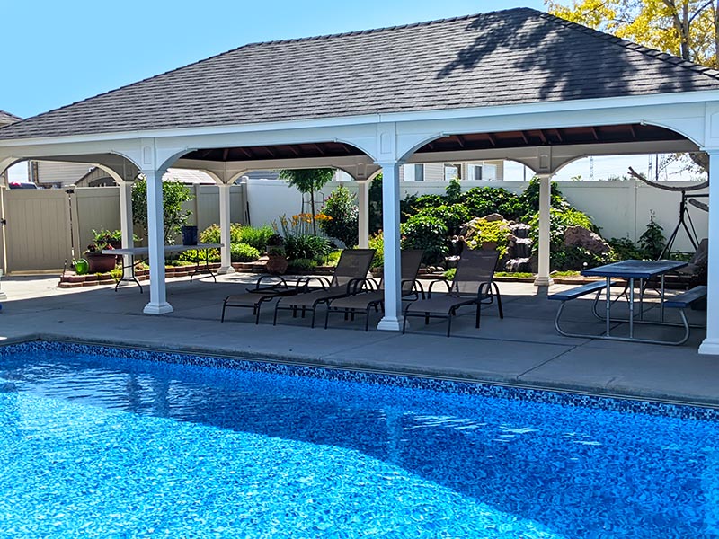 large pavilion next to a swimming pool with outdoor furniture